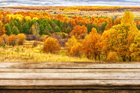 Empty wooden table with blurred picturesque autumn landscape of panoramic view from hill to lowland...