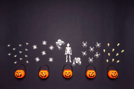 Halloween composition. Pumpkin baskets with skeletons, flies and spiders on black background. Happy...