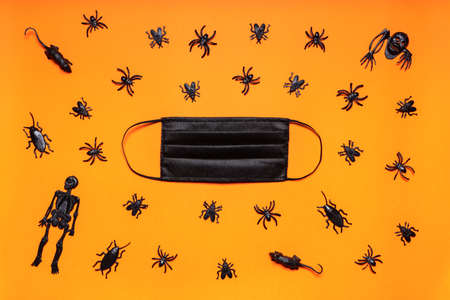 Halloween party during COVID-19 pandemic. Medical mask and black skeletons, spiders, flies, bugs and...