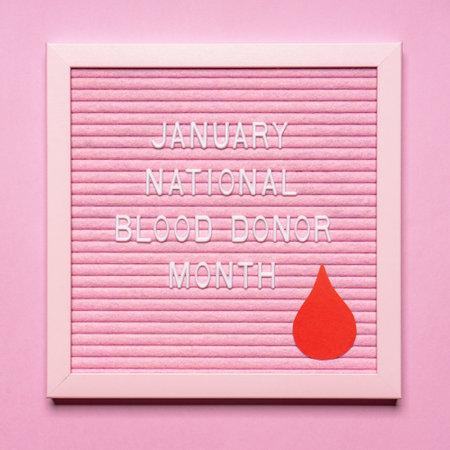 Text JANUARY NATIONAL BLOOD DONOR MONTH with red drop on pink letterboard. Annual national red cross campaign in January, 2021. Charity, donation, volunteer concept. Health care and medicine.の写真素材