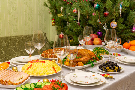 Festive Christmas served table against beautiful green pine tree decorated with many colorful new...