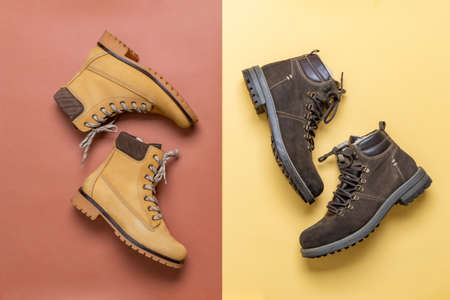 Two pairs of yellow and brown men's and women's winter suede leather stylish boots on color background. Casual trendy footwear, shopping, sale, shoes fashion concept. Flat lay, top view.の写真素材