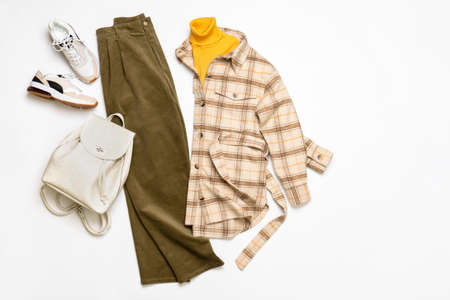 Female winter or autumn stylish clothing set. Plaid checkered shirt, yellow sweater, green corduroy trousers, sneakers and backpack. Trendy fashionable casual clothes. fashion concept.の写真素材