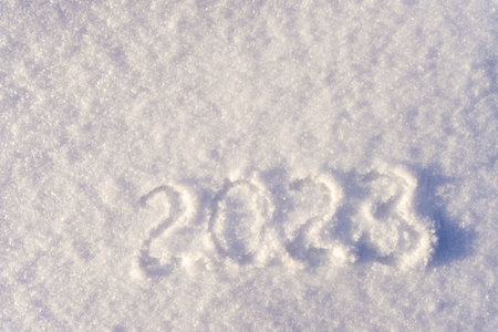 Text 2023 written on white fresh sparkling snow on sunny winter day. Merry Christmas and Happy New Year. Winter holiday concept. Flat lay, top view, copy space.の写真素材