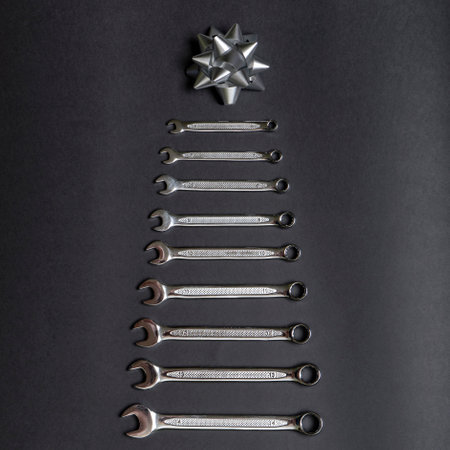 Christmas tree made of wrenches on black background. Tools spanners. Technique repair, equipment for mechanical service, labor's holiday concept. Chrismas or New year concept. Flat lay, top view.の写真素材