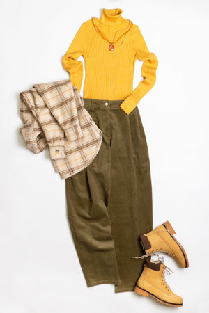 Female winter or autumn stylish clothing set. Plaid checkered shirt, yellow sweater and leather boots, green corduroy trousers, accessories. Trendy fashionable casual clothes. fashion concept.の写真素材