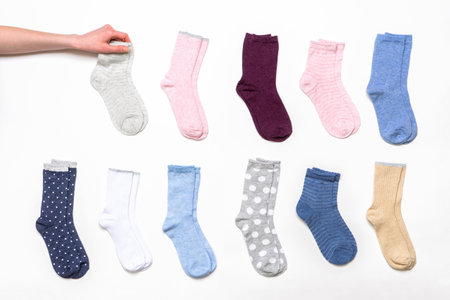 Female hand holding socks among women's cotton socks set on white background. fashionable socks store. Socks shopping, sale, merchandise, advertisement concept.の写真素材
