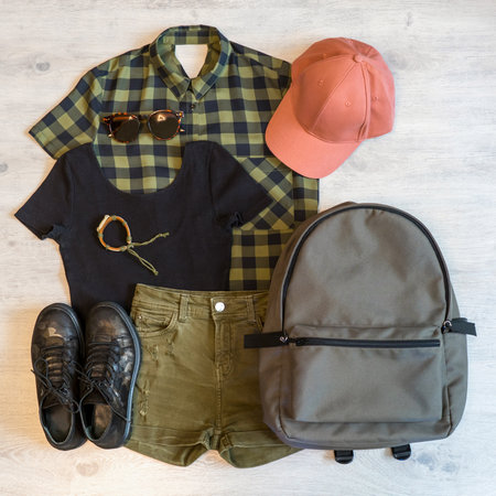 Stylish women's or teenager's clothing set with accessories: checkered shirt, black jersey top, green jeans shorts, pink cap, backpack, sunglasses, bracelet and boots in military style. summer outfitの写真素材