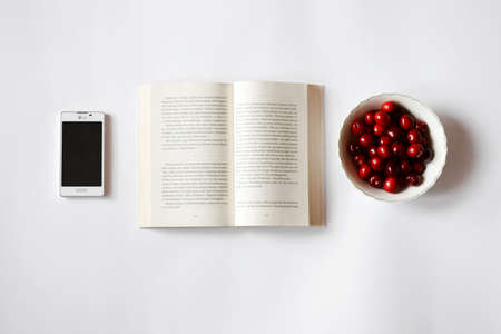 book, cellphone and cherriesの写真素材