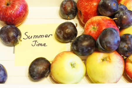 Summer time: apples and plums on the wooden deskの写真素材