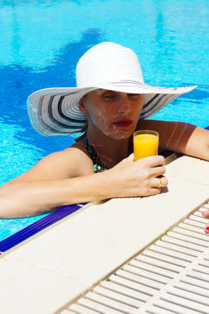 beautiful girl in a hat relaxing near a swimming pool