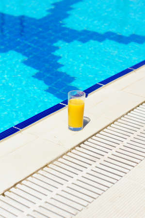 Orange juice on the border of poolの写真素材