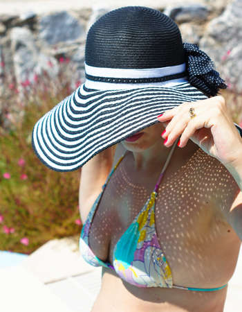 beautiful girl in a hat relaxing near a swimming poolの写真素材