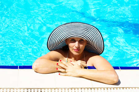beautiful girl in a hat relaxing near a swimming pool