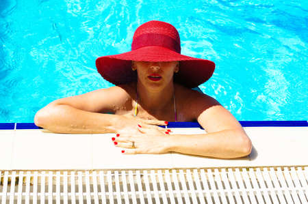 beautiful girl in a hat relaxing near a swimming poolの写真素材