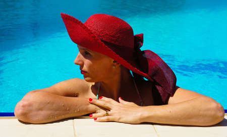 beautiful girl in a hat relaxing near a swimming poolの写真素材