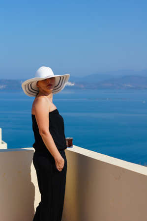 Beautiful woman in a straw hat on the villa's roof with view to Aegean seaの写真素材