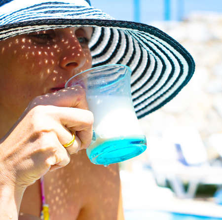 beautiful girl in a hat relaxing near a swimming poolの写真素材