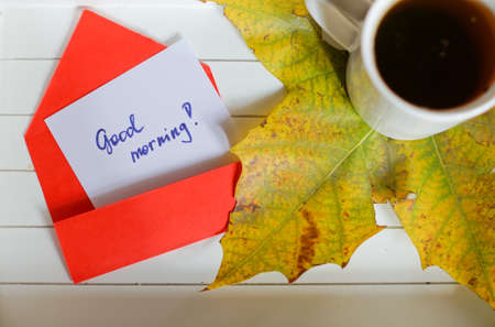 Autumn time: cup of tea, maple yellow leave and Good morning noteの写真素材