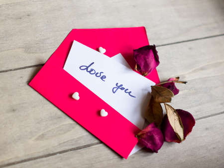 Red envelope with note, hearts and rose petalsの写真素材