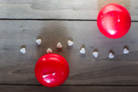 Red candles and white hearts on the wooden desk