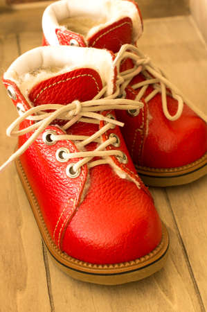 Red children winter shoes on the wooden の写真素材