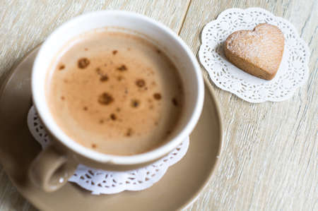 Cup of coffee with milk and biscuit on the tableの写真素材