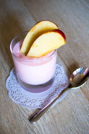 Glass of yoghurt and apple slices on the tableの写真素材