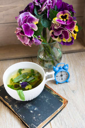 Glasses of green mint tea and vase with fresh violas on the tableの写真素材
