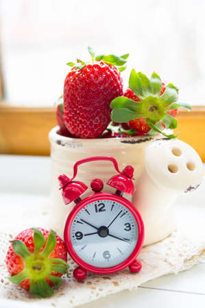 Fresh strawberries on the table and old-styled red clockの写真素材