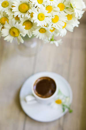 Cup of black coffee and daisy flowers on the old tableの写真素材