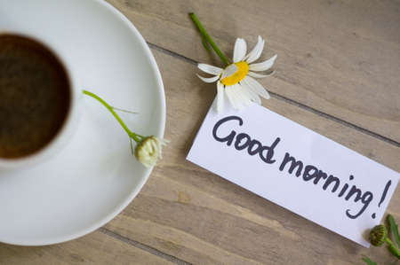 Cup of black coffee and daisy flowers on the old tableの写真素材