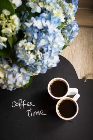 Hydrangea flowers in a vase, cup of coffee and noteの写真素材