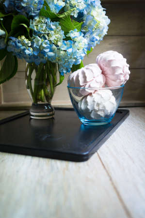 Blue pastel color hydrangea flowers and sweets on wooden tableの写真素材