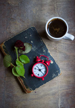 Cup of coffee, old book and dry red rose on the tableの写真素材
