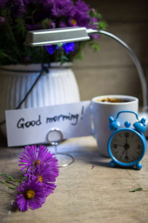 Cup of coffee and aster flowers in a vase on the wooden table