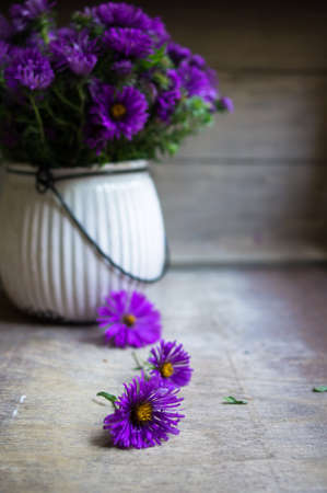 Blue aster flowers in a vase on the old wooden tableの写真素材