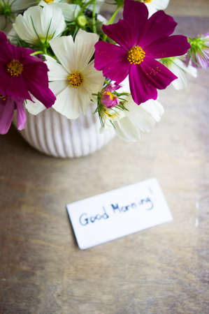 Vase with coreopsis flowers on the wooden table and good morning noteの写真素材