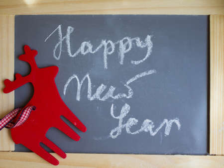 Red ceramic cup with tea and lemon, Happy New Year sign made with chalk, and christmas decoration