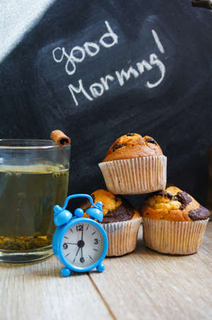 Cup of hot green tea, cupcakes and Good morning note on the wooden tableの写真素材