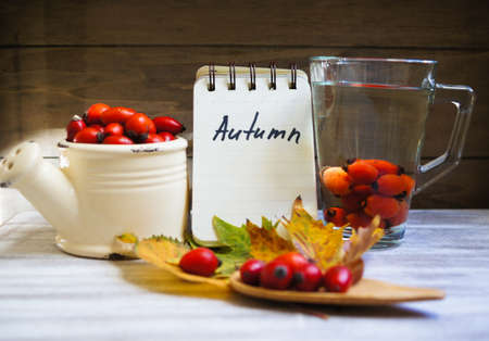 Hot hip tea with berries on the woodden background with note Autumnの写真素材