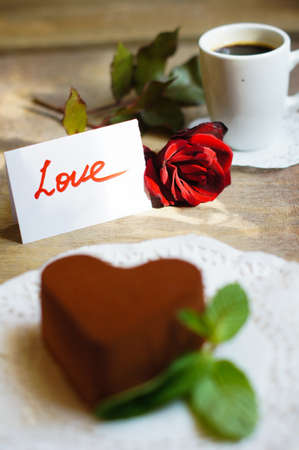 Tiramisu cake heart shaped with fresh mint, tea, red roses and note on the wodden backgroundの写真素材