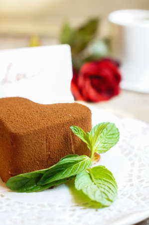 Tiramisu cake heart shaped with fresh mint, tea, red roses and note on the wodden backgroundの写真素材