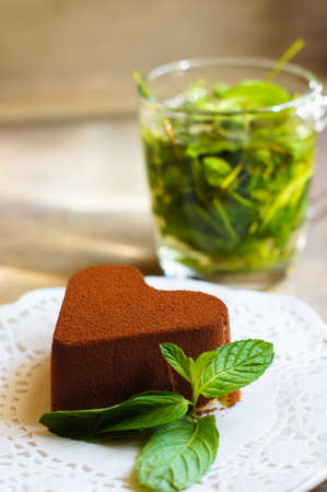 Tiramisu cake heart shaped with fresh mint, tea, red roses and note on the wodden backgroundの写真素材