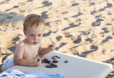 thoughtful baby boy sitting on the beachの写真素材