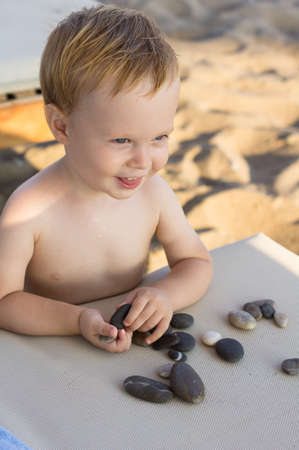 thoughtful baby boy sitting on the beachの写真素材