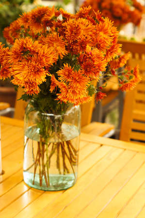 Autumn flowers in the vase on the tableの写真素材