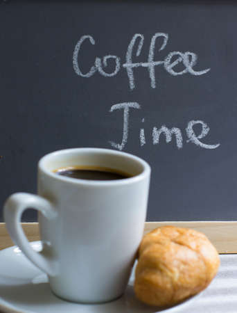 Cup of black coffee and croissants on the chalkboard with coffee time noteの写真素材