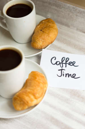 Cup of black coffee and croissants on the chalkboard with noteの写真素材