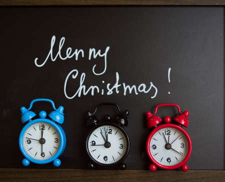 Merry Christmas is written on a blackboard and old-styled clocksの写真素材